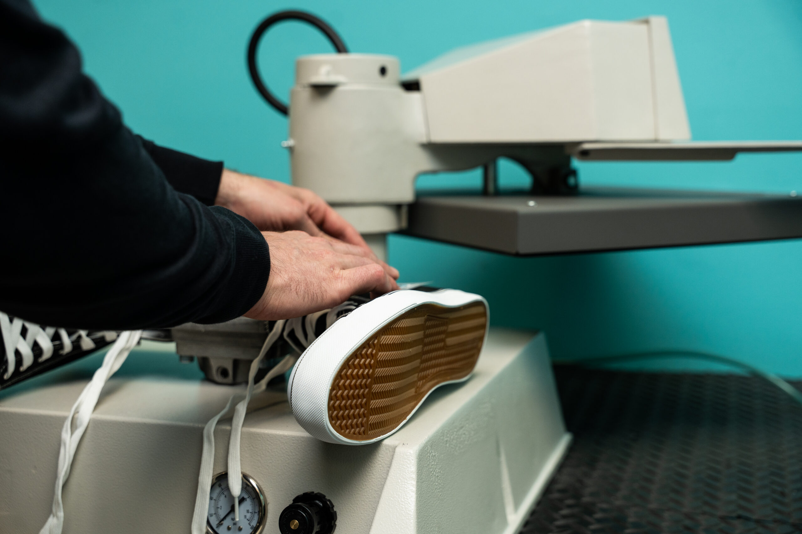 Operator positioning a sneaker on a heat press machine to apply a custom transfer using professional heat press equipment from Insta Graphic Systems