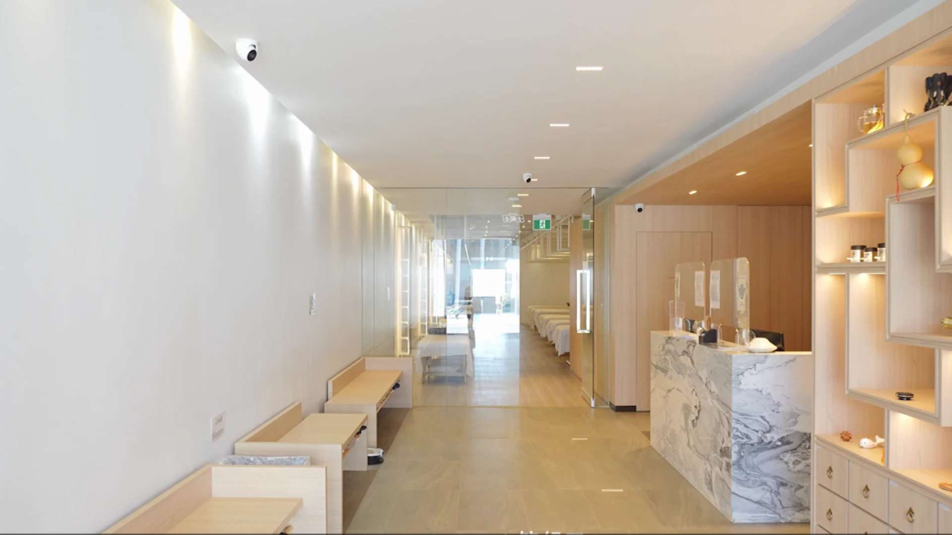 Osteo Tuina massage clinic interior with marble reception desk, light wood finishes, and treatment rooms in the background.
