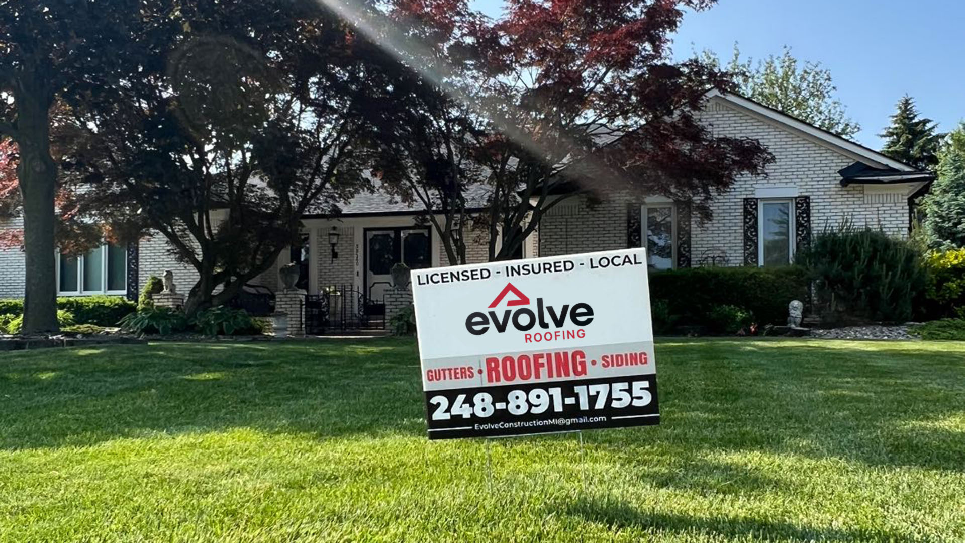 Evolve Roofing yard sign in front of a Clinton Twp home with a newly installed roof.