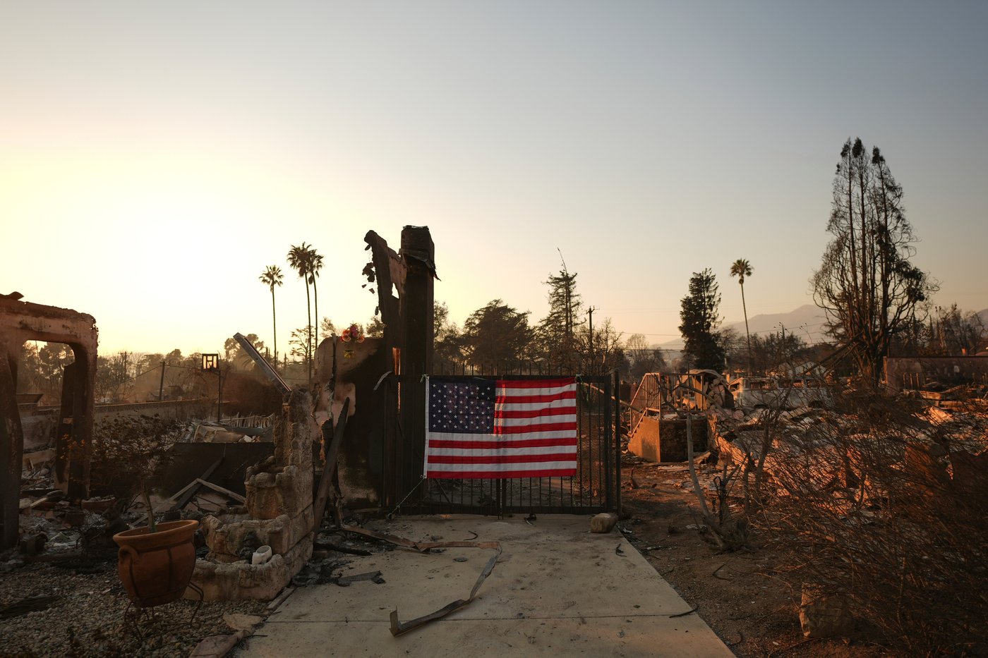 FILE - An American flag hangs on the gate of a home destroyed by the Eaton Fire in Altadena, Calif., Jan. 10, 2025. (AP Photo/Jae C. Hong, File)