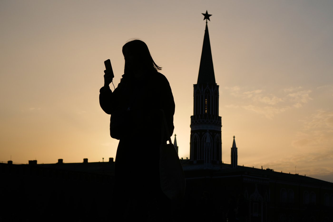 FILE - A woman checks her phone as she walks through Red Square at sunset, in Moscow, Tuesday, March 31, 2026. (AP Photo/Pavel Bednyakov, File)