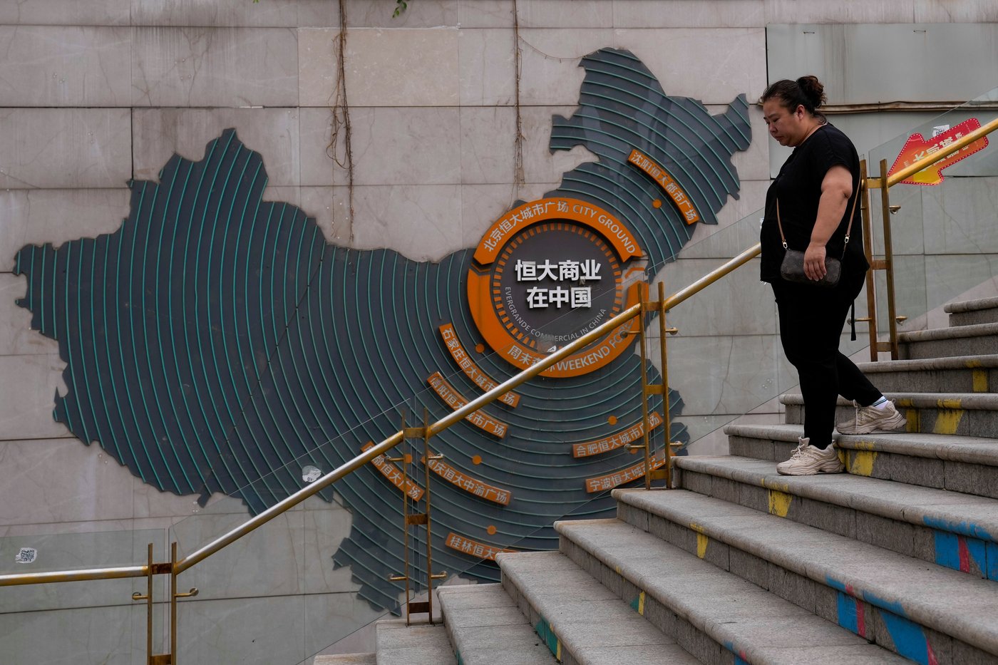 FILE - A woman walks by a map showing Evergrande development projects in China, as she heads to an Evergrande city plaza in Beijing on Sept. 18, 2023. (AP Photo/Andy Wong, File)