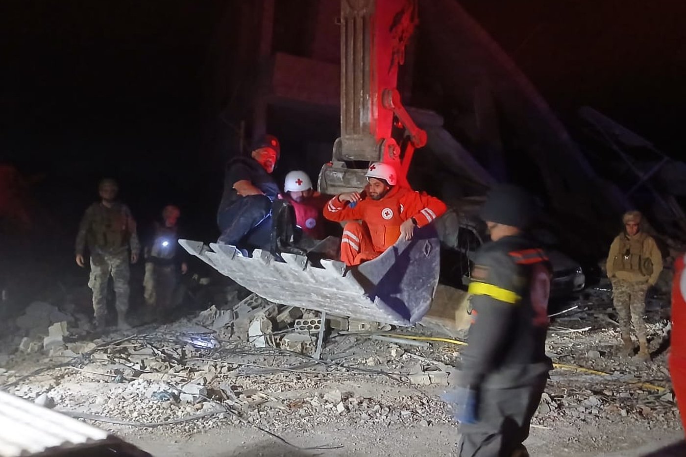 This photo released by the Lebanese Civil Defense, show Lebanese Red Cross volunteers and a Civil Defense worker sit on a excavator carrying the body of the Lebanese journalist Amal Khalil working for the daily Al-Akhbar newspaper killed in an Israeli airstrike, in al-Tiri village, south Lebanon, Wednesday, April 22, 2026. (Lebanese Civil Defense via AP)