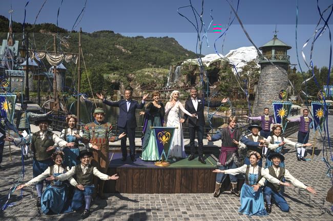 Paul Chan, Hong Kong's financial secretary, left, and Josh D'Amaro, chairperson of Disney Experiences, right, pose with performers in front of the press during the opening ceremony of the World of Frozen themed area at Disneyland Resort in Hong Kong, Monday, Nov. 20, 2023. (AP Photo/Louise Delmotte)