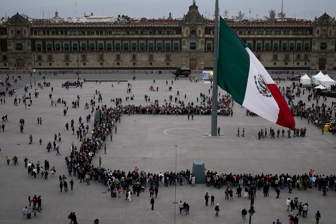People watch the lowering of the flag ceremony at the Zocalo in Mexico City, Saturday, Jan. 20, 2024. (AP Photo/Natacha Pisarenko)