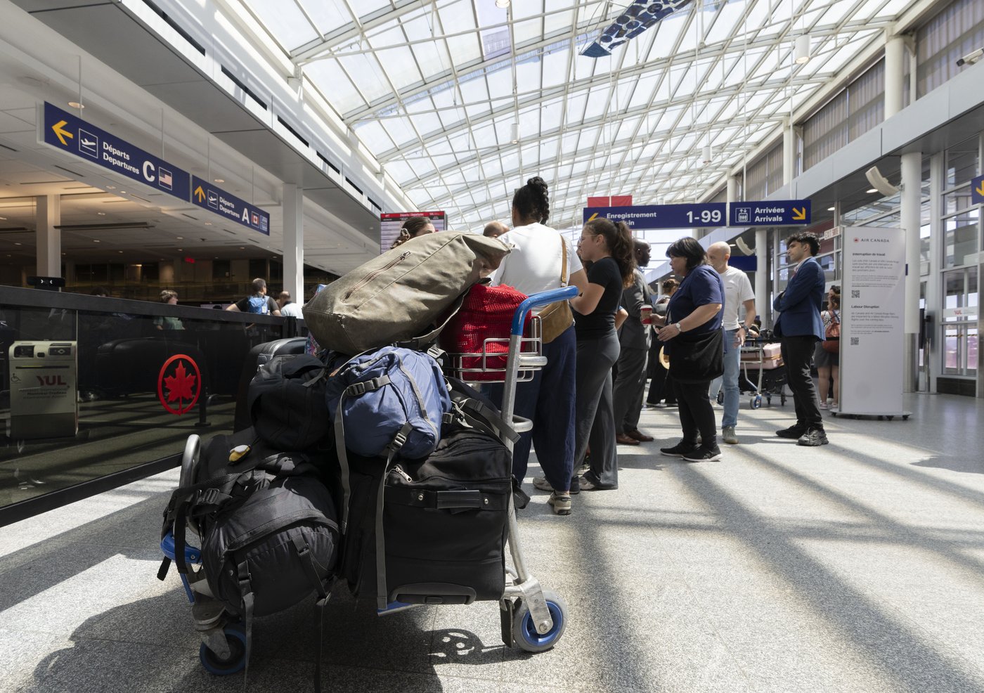 Travellers wait at the Air Canada counter in Montreal-Pierre Elliott Trudeau International Airport in Dorval, Que., Friday, Aug. 15, 2025. THE CANADIAN PRESS/Christinne Muschi