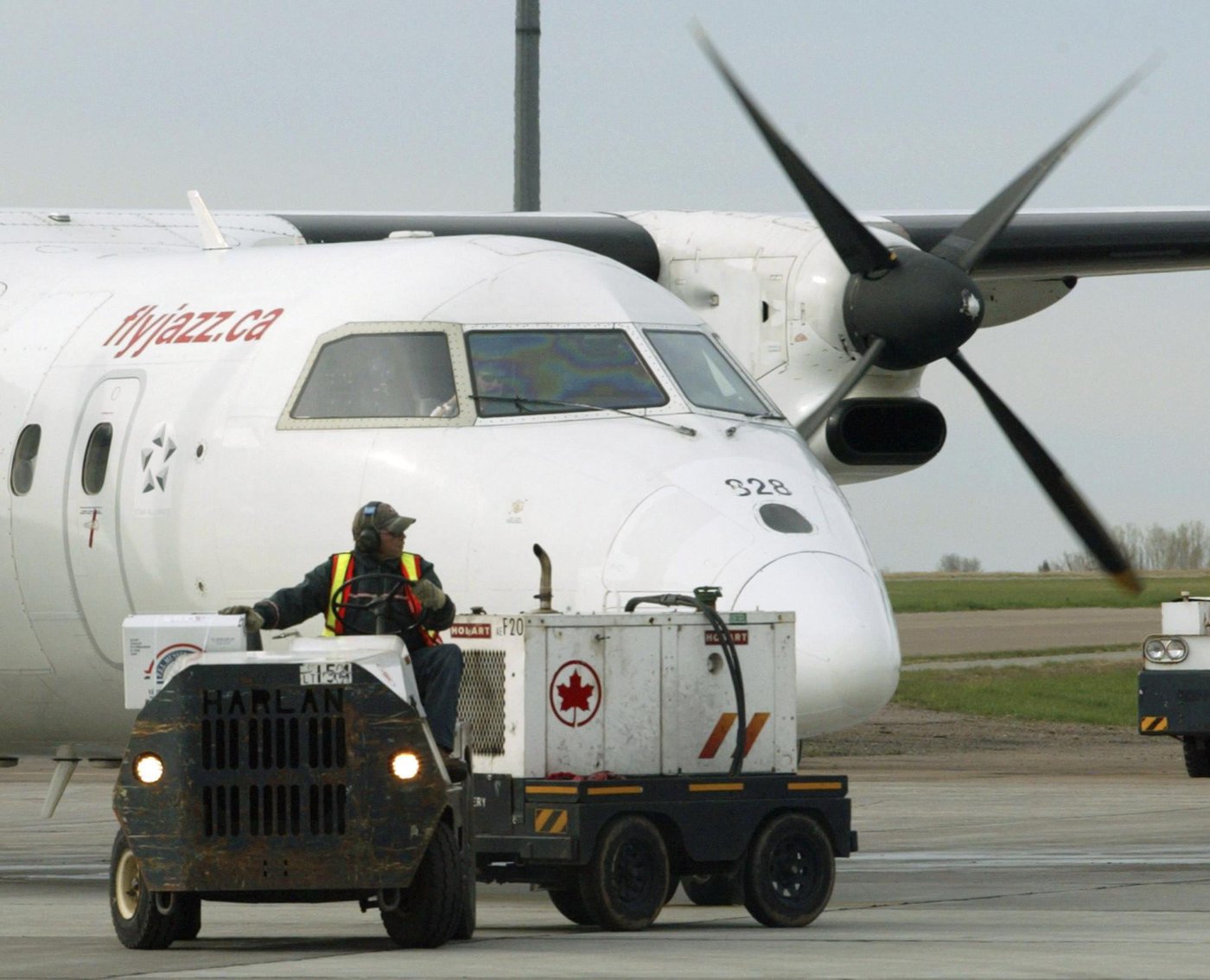 An Air Canada employee drives equipment from in front of an Air Jazz flight at the airport in Charlottetown on Wednesday May 26, 2004. THE CANADIAN PRESS/Adrian Wyld