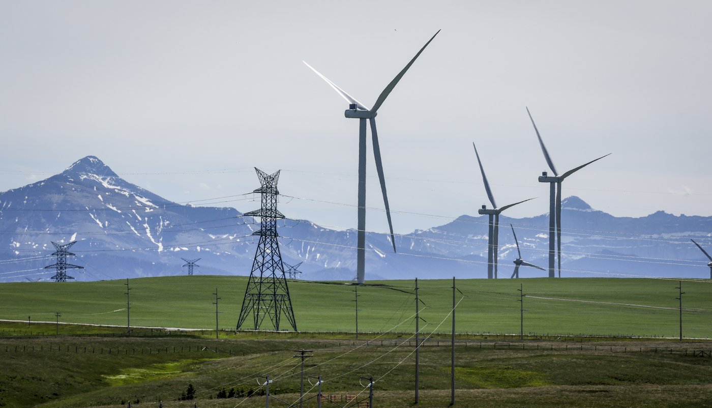 Power transmission lines and wind turbines as seen with the Rocky Mountains in the background near Pincher Creek, Alta., Thursday, June 6, 2024. THE CANADIAN PRESS/Jeff McIntosh