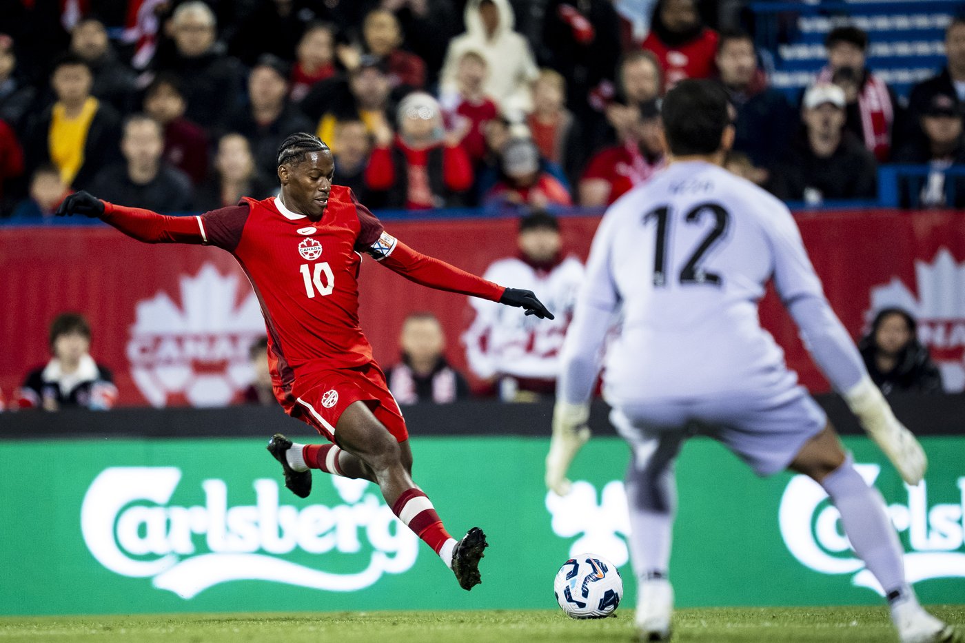 Canada's Jonathan David (10) shoots on net while Australia goalkeeper Paul Izzo (12) defends during first half international friendly soccer action, in Montreal, on Friday, October 10, 2025. THE CANADIAN PRESS/Christopher Katsarov