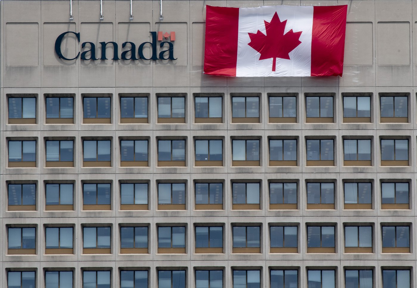 A giant Canadian flag hangs on the side of a government office building in downtown Ottawa on Tuesday, June 30, 2020. THE CANADIAN PRESS/Adrian Wyld