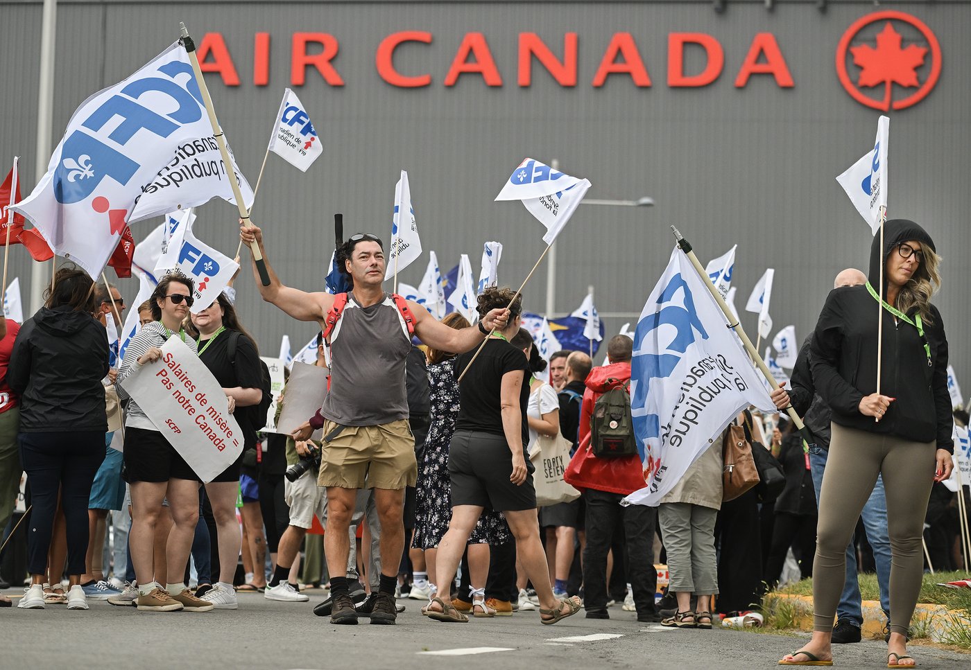 People protest outside Air Canada headquarters in Montreal, Sunday, Aug. 17, 2025, after the federal government intervened in the labour dispute between the airline and the union representing its flight attendants, ordering binding arbitration and operations to resume. THE CANADIAN PRESS/Graham Hughes