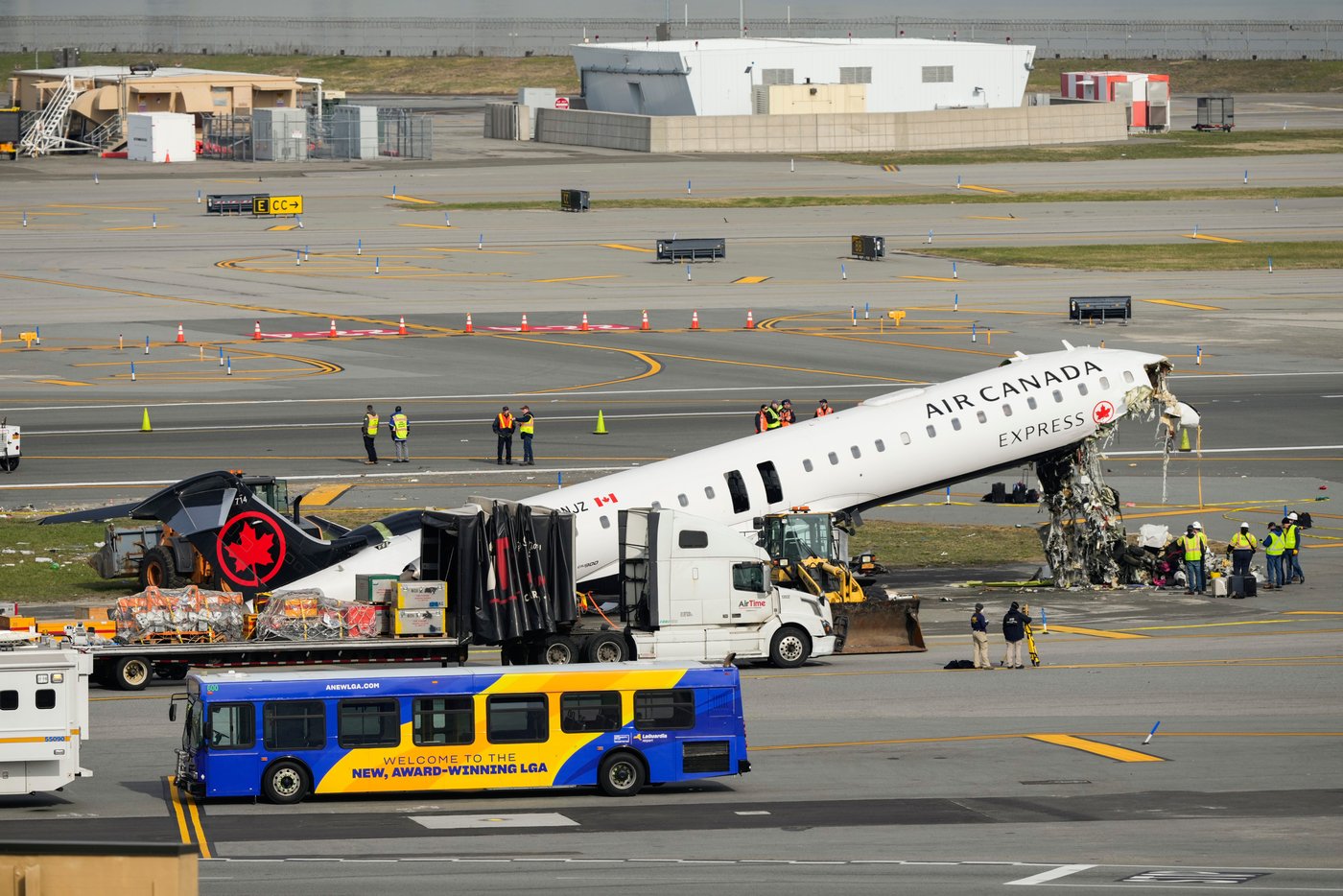 Officials inspect the wreckage of an Air Canada Express jet, Wednesday, March 25, 2026, just off the runway where it had collided with a Port Authority fire truck Sunday night at LaGuardia Airport in New York. (AP Photo/Yuki Iwamura)
