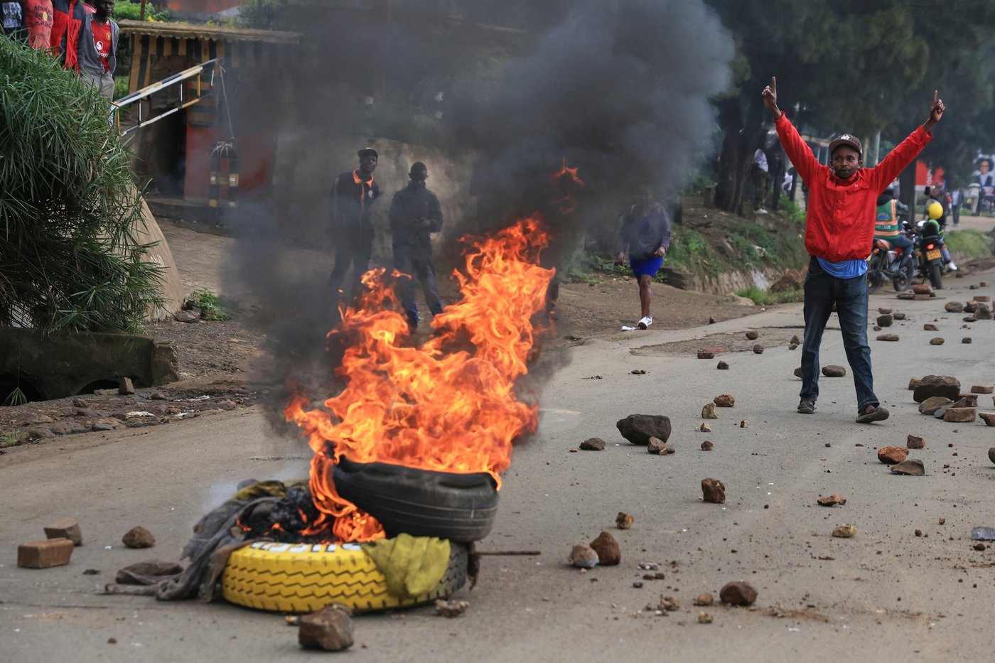 A man demonstrates near a fire during a public transport strike over fuel prices in Nairobi, Kenya, Monday, May 18, 2026. (AP Photo/Andrew Kasuku)