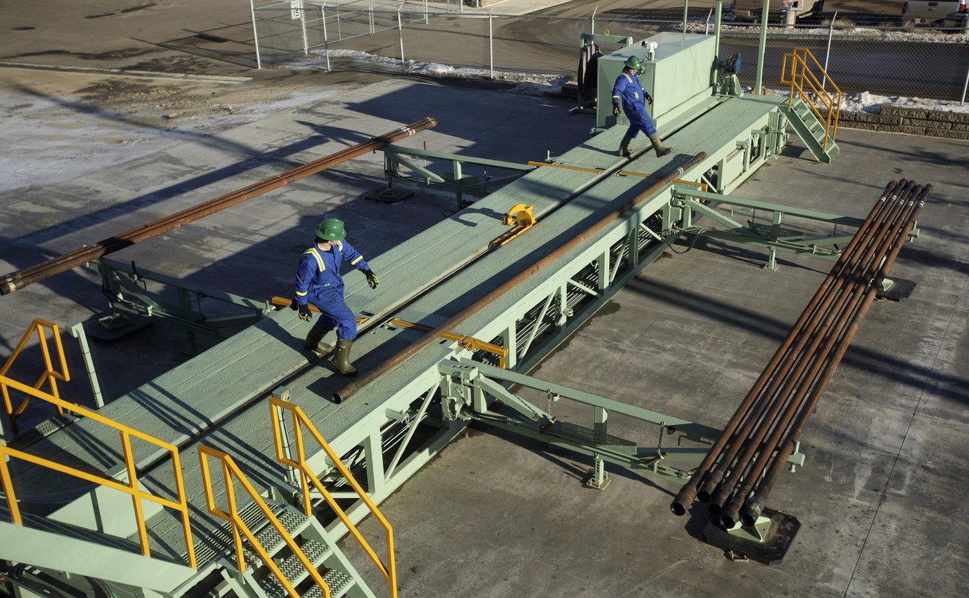 Trainees roll pipe off the catwalk during a training session to lay down drill pipe on a rig floor at Precision Drilling in Nisku, Alta., on Friday, Jan. 20, 2016. THE CANADIAN PRESS/Jason Franson