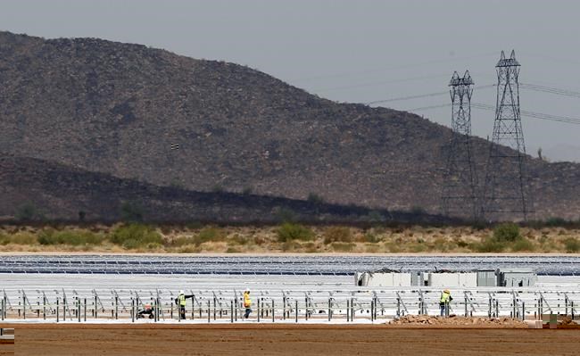 FILE - Workers continue to build rows of solar panels at a Mesquite Solar 1 facility under construction in Arlington, Ariz., Sept. 30, 2011. One of President Joe Biden's signature laws aimed to invigorate renewable energy manufacturing in the U.S. It will also helped a solar panel company reap billions of dollars. Arizona-based First Solar is one of the biggest early winners from the Democrats' Inflation Reduction Act, offering a textbook case of how the inside influence game works in Washington.(AP Photo/Ross D. Franklin, File)