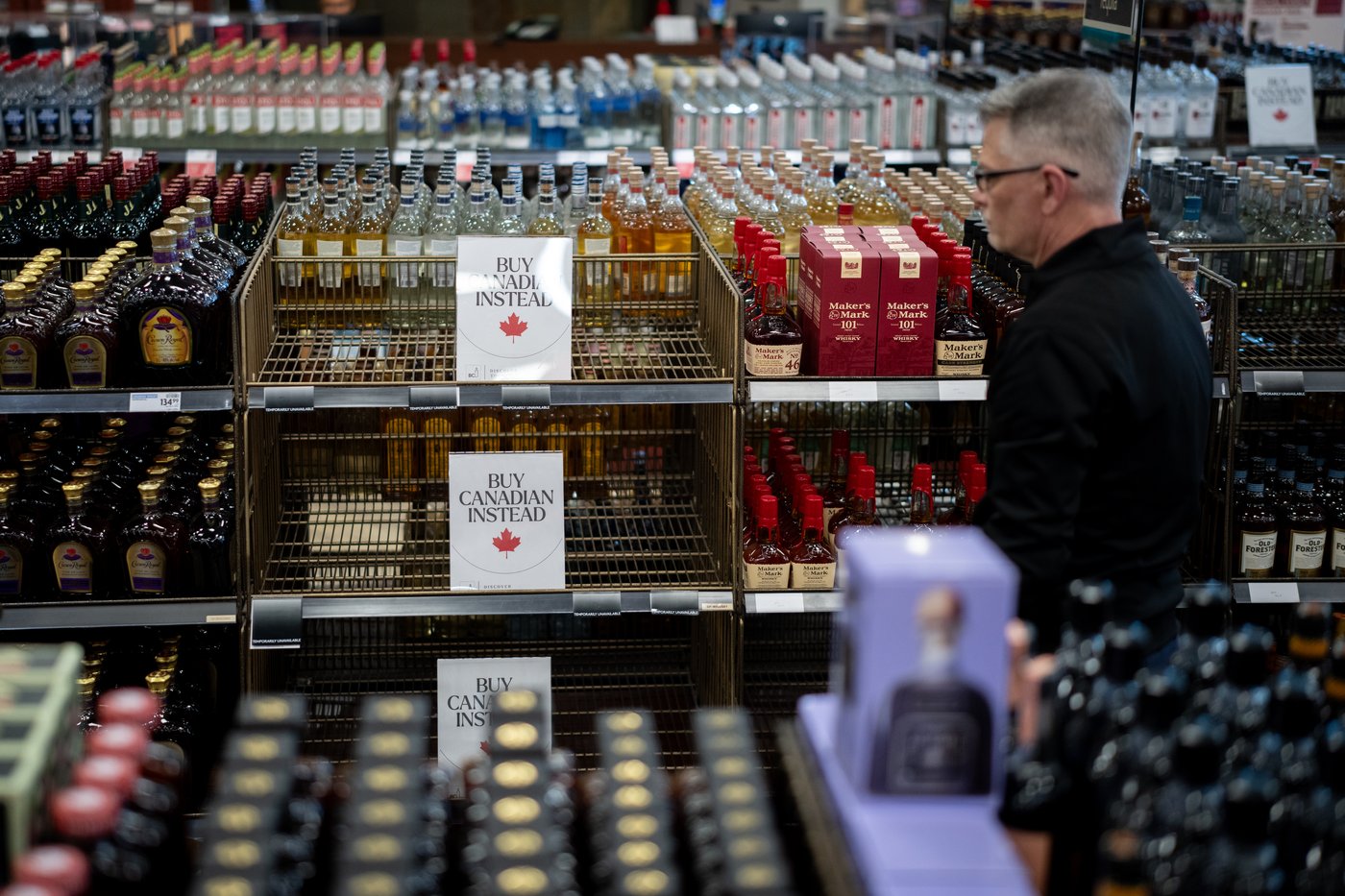 A liquor store employee looks at a sign placed in the American whiskey section at a B.C. Liquor Store after top selling American made products have been removed from shelves in Vancouver, B.C., Sunday, Feb. 2, 2025. THE CANADIAN PRESS/Ethan Cairns