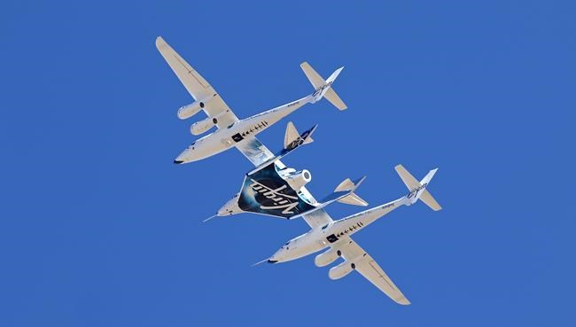 FILE - Virgin Galactic's VSS Unity departs Mojave Air & Space Port in Mojave, Calif., for the final time as Virgin Galactic shifts its SpaceFlight operations to New Mexico, Feb. 13, 2020. Virgin Galactic is taking its first space tourists on a rocket ship ride after years of delays, including one passenger who bought his ticket 18 years ago and a mother-daughter duo from the Caribbean. (Matt Hartman via AP, File)