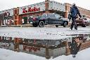A Tim Hortons store is reflected in a rain puddle as business goes on despite a wildfire risk in Fort McMurray, Alta., Thursday, May 16, 2024.THE CANADIAN PRESS/Jeff McIntosh