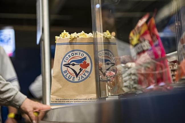 With foot-long hotdogs roughly $13 and 515-mL premium draft beers nearing $15, it can be expensive to dine at the Rogers Centre, but many Canadians have found ways to save on food at the Toronto venue, including sharing popcorn amongst friends or attending on days when hot dogs are sold for a loonie. Fans line up for food during the Toronto Blue Jays home opener on Friday, April 8, 2022. THE CANADIAN PRESS/Christopher Katsarov