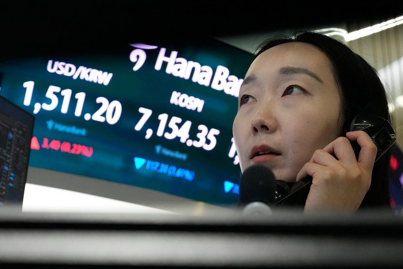 A currency trader talks on the phone near a screen showing the Korea Composite Stock Price Index (KOSPI) and the foreign exchange rate between U.S. dollar and South Korean won, left, at the foreign exchange dealing room of the Hana Bank headquarters in Seoul, South Korea, Wednesday, May 20, 2026. (AP Photo/Ahn Young-joon)