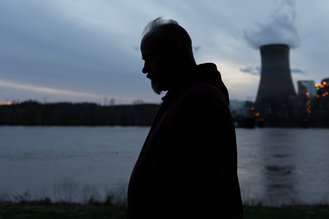 Eric Pinson, manager and resident of the Lock 24 RV Park and Campground, one of two such locations he manages in the area, is silhouetted at dusk as the coal-fired Mountaineer Power Plant, near New Haven, W.Va., stands across the Ohio River from the campground, Friday, March 13, 2026, in Racine, Ohio. (AP Photo/Carolyn Kaster)