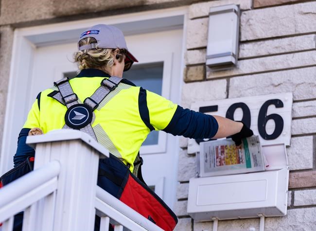 Postal workers could go on strike Friday morning if no deal is reached between the Crown corporation and the union. A Canada Post mail carrier delivers flyers on their route in Montreal on Wednesday, Nov.13, 2024. THE CANADIAN PRESS/Christinne Muschi
