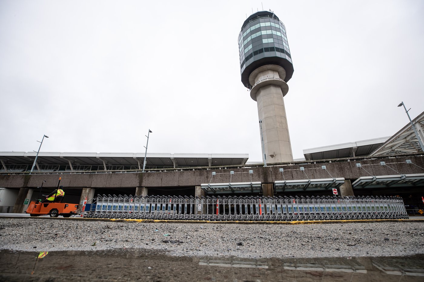 A worker moves luggage trolleys outside Vancouver International Airport in Richmond, B.C., on Thursday, Dec. 31, 2020. THE CANADIAN PRESS/Darryl Dyck