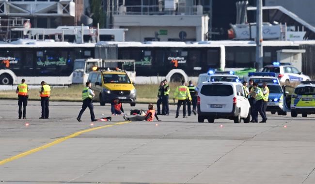Emergency vehicles from the police, fire department and airport security are parked on the apron of Frankfurt Airport, where a few activists have taped themselves up, in Frankfurt, Germany, Thursday, July 25, 2024. (Arne Dedert/dpa via AP)