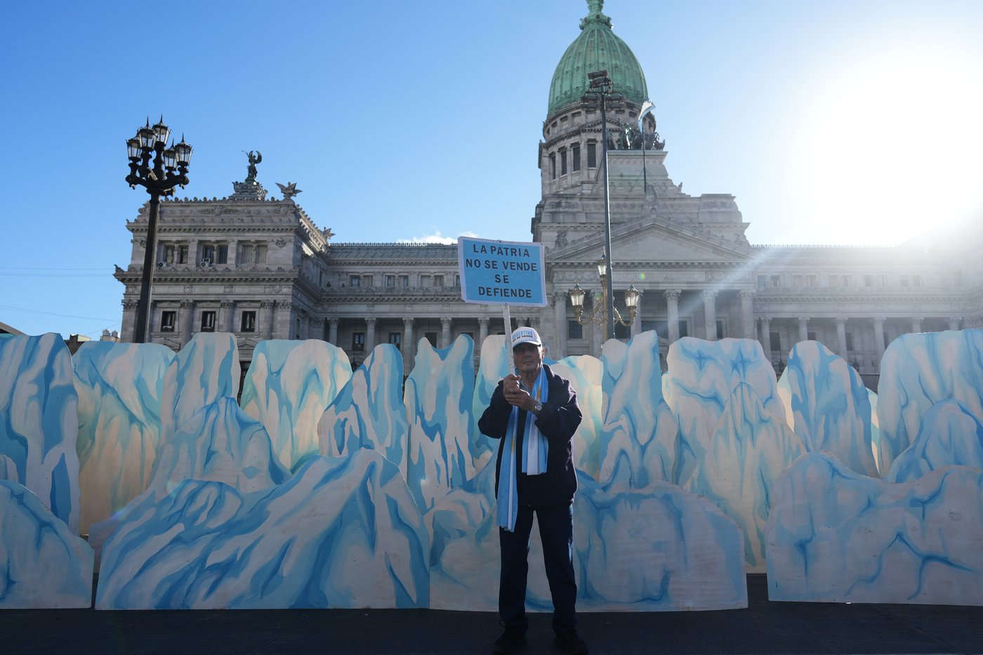 A demonstrator holds a banner that reads in Spanish, "The homeland is not for sale, it's defended" as lawmakers debate the Javier Milei government's proposal to reform the glacier protection law, outside Congress in Buenos Aires, Argentina, Wednesday, April 8, 2026. (AP Photo/Rodrigo Abd)