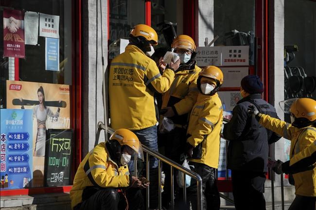 Delivery workers line up outside a pharmacy store to collect their customer's online drug orders after authorities started easing some of the anti-virus controls in Beijing, Thursday, Dec. 8, 2022. China is the last major country still trying to stamp out transmission of the virus while many nations switch to trying to live with it. As they lift restrictions, Chinese officials have also shifted to talking about the virus as less threatening — a possible effort to prepare people for a similar switch. (AP Photo/Andy Wong)