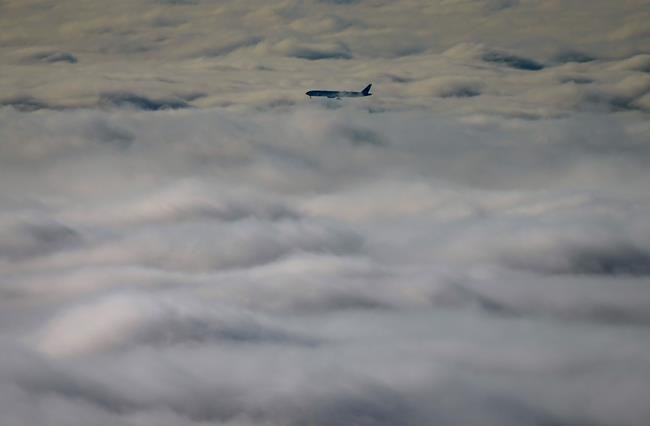An airplane descends into the fog blanketing the region while on approach to land at Vancouver International Airport, in Richmond, B.C., on Sunday, November 26, 2023. A draft report from a United Nations agency gives Canada a C grade for flight safety and oversight, down from A+. THE CANADIAN PRESS/Darryl Dyck