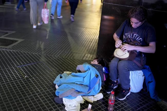 Cintia Barros' son Alessandre sleeps on the ground as she begs on a street corner sidewalk in downtown Buenos Aires, Argentina, Tuesday, Sept. 3, 2024. (AP Photo/Natacha Pisarenko)