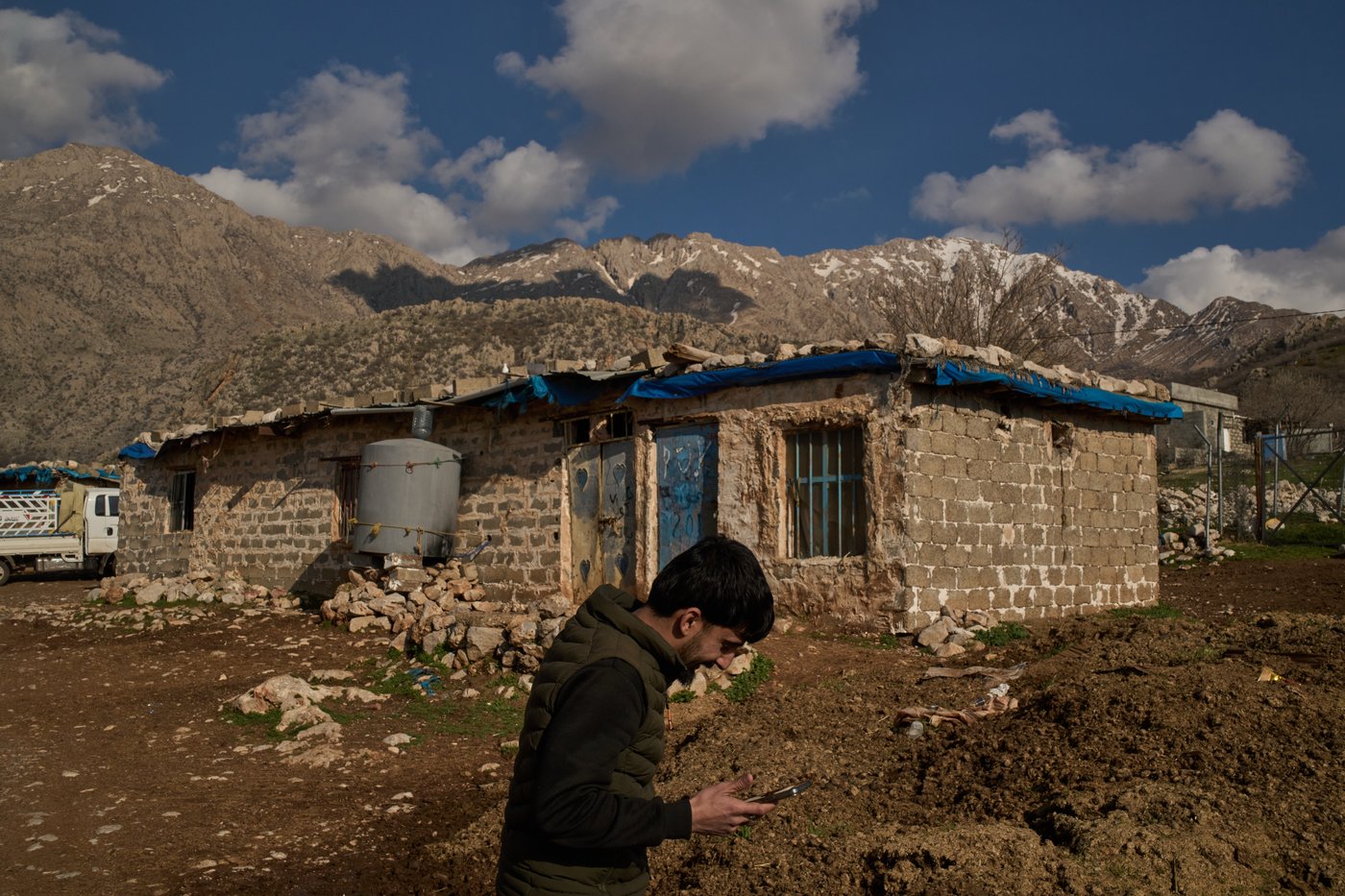 Bilal Osman, 25, an Iraq-Iran cross-border smuggler, speaks on the phone with a partner in Iran as he stands at a compound in a village in the mountainous Kurdish region near Halabja, Iraq, Tuesday, March 17, 2026. (AP Photo/Leo Correa)