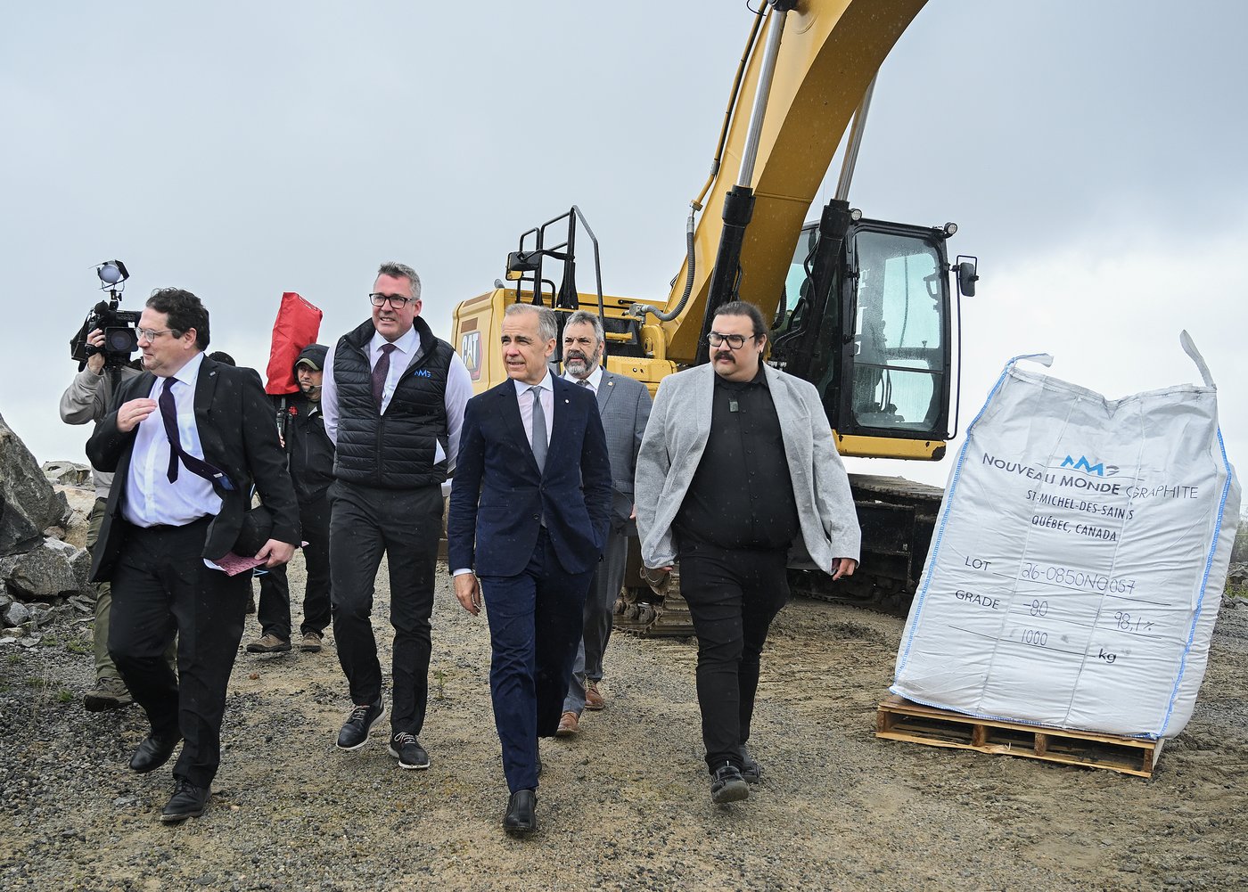 Prime Minister Mark Carney, centre, arrives to make an announcement at the Nouveau Monde Graphite mine alongside, from left, Quebec Economy Minister Bernard Drainville, NMG CEO Eric Desaulniers, Mayor of Saint-Michel-des-Saints Mario Venne and Chief of the Atikamekw Council of Manawan Sipi Flamand in Saint-Michel-des-Saints, Que., on Tuesday, May 19, 2026. THE CANADIAN PRESS/Graham Hughes