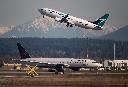 An Air Canada flight departing for Toronto, bottom, taxis to a runway as a WestJet flight bound for Palm Springs takes off at Vancouver International Airport, in Richmond, B.C., on Friday, March 20, 2020. THE CANADIAN PRESS/Darryl Dyck