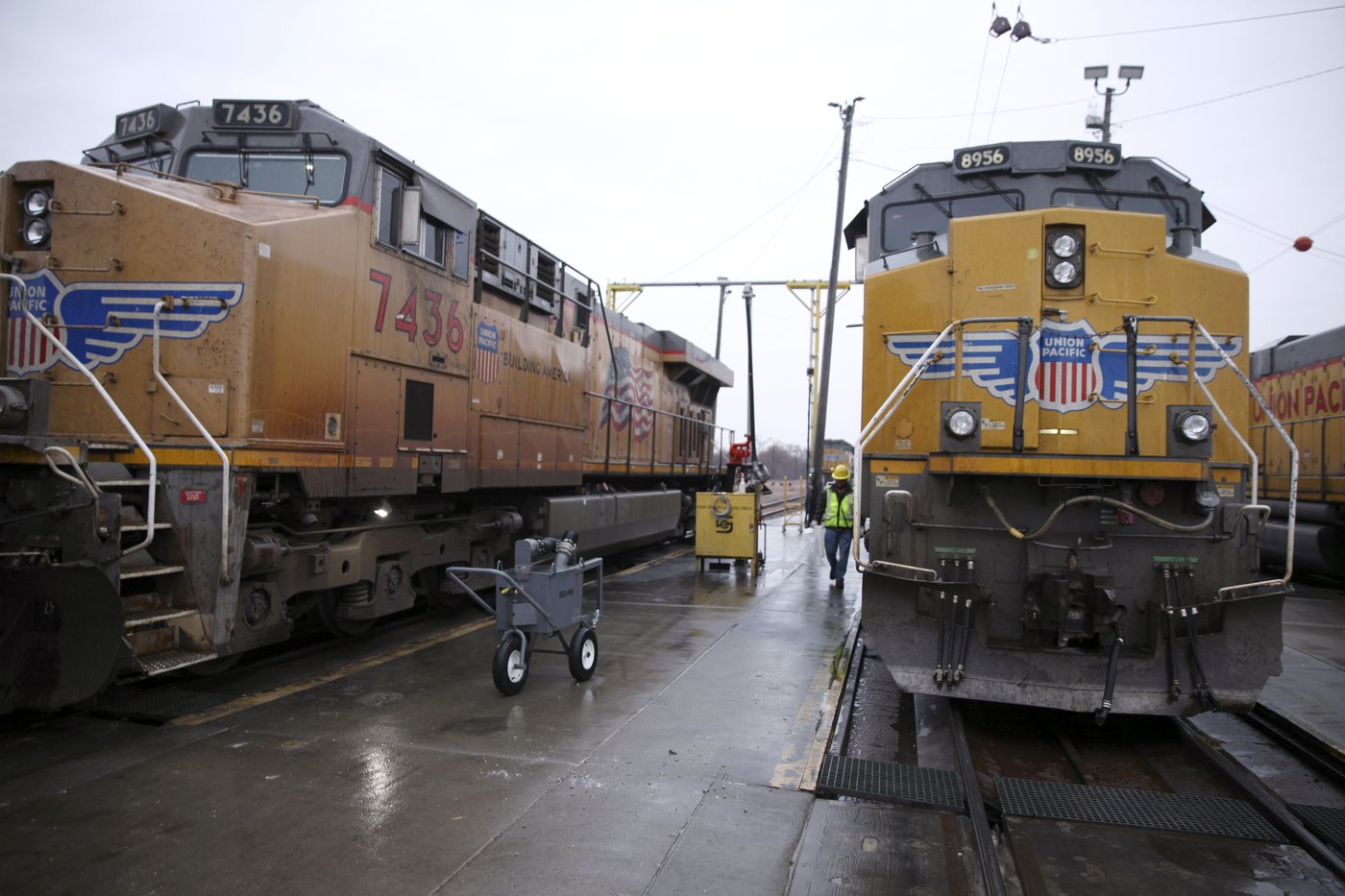 A Union Pacific worker walks between two locomotives that are being serviced in a rail yard in Council Bluffs, Iowa, on Dec. 15, 2023. (AP Photo/Josh Funk)