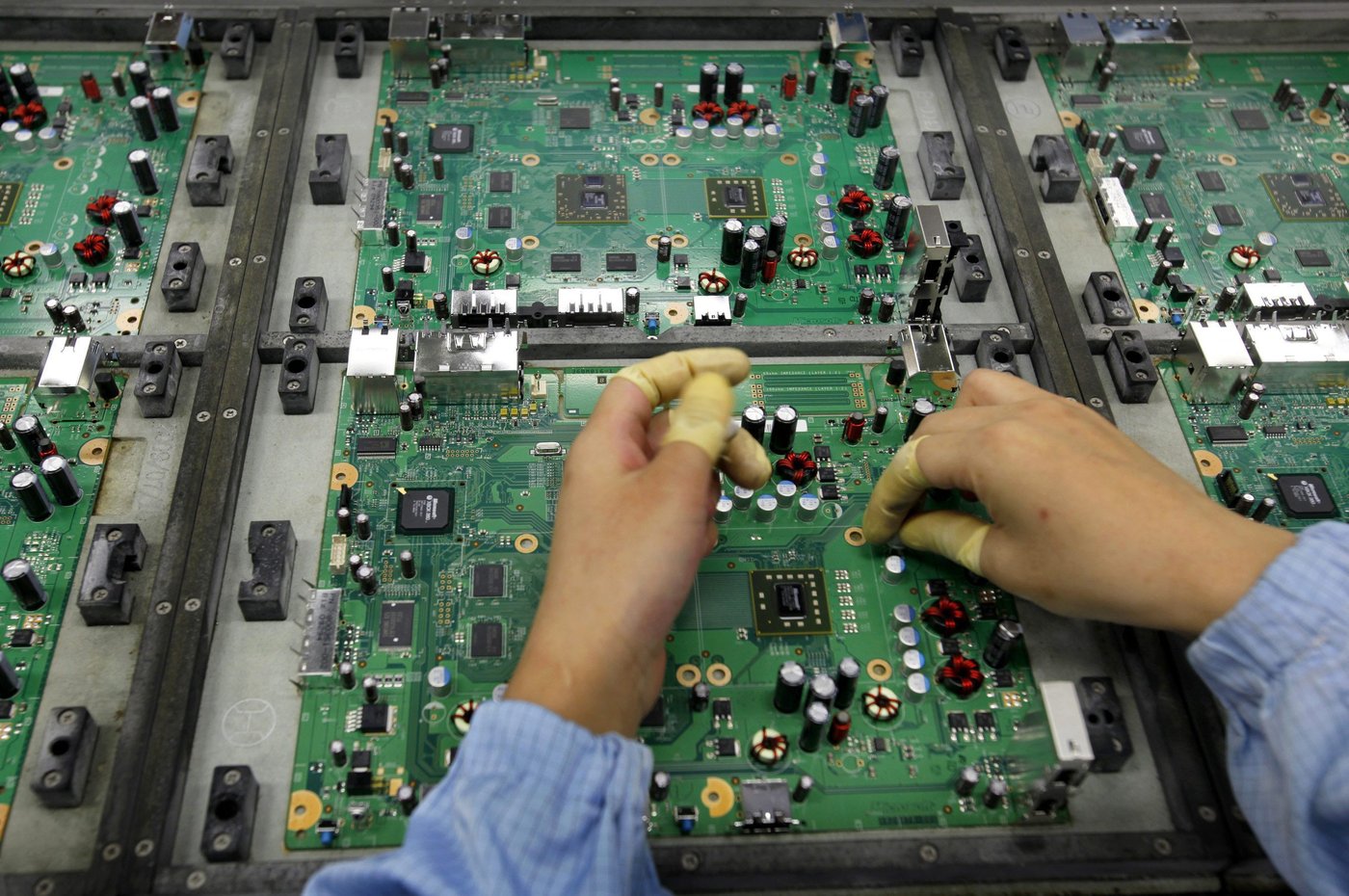 A Celestica employee works on a motherboard at the Celestica Technology Co. Ltd, a Canada-based electronics company, in China's southern city, Dongguan, Wednesday, July 29, 2009. (AP Photo/Vincent Yu)