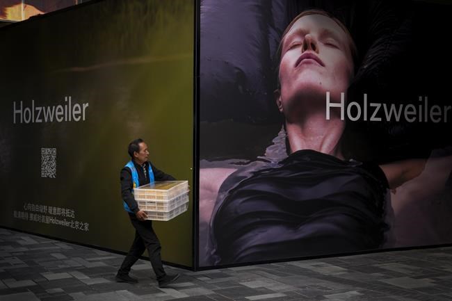 FILE - A delivery worker walks by a foreign fashion storefront under renovation at an outdoor shopping mall in Beijing on Sept. 20, 2023. The world economy is losing momentum in the face of higher interest rates, the ongoing war in Ukraine and widening geopolitical rifts, the International Monetary Fund warned Tuesday Oct. 10, 2023. (AP Photo/Andy Wong, File)
