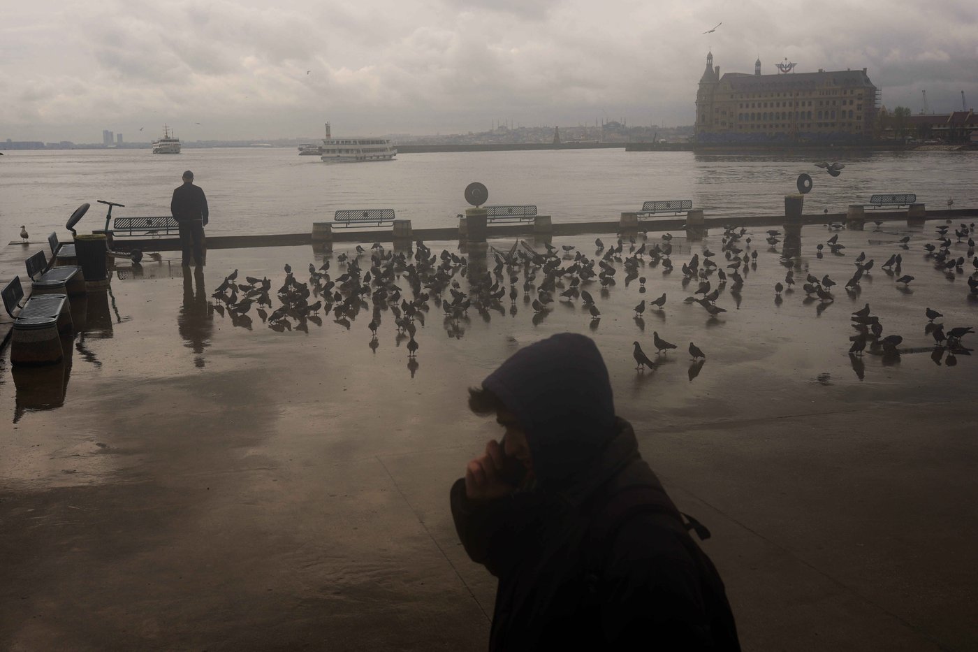 A man stands next to the Bosphorus at Kadikoy ferry terminal on a rainy day in Istanbul, Turkey, Wednesday, April 22, 2026. (AP Photo/Francisco Seco)