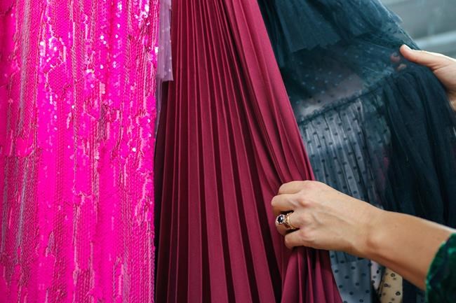 Experts say people trying to reduce their dry-cleaning bills should consider steaming clothes or hand washing them. A woman shows the variety of formal wear in her Toronto store, Friday, Sept. 23, 2022. THE CANADIAN PRESS/Alex Lupul