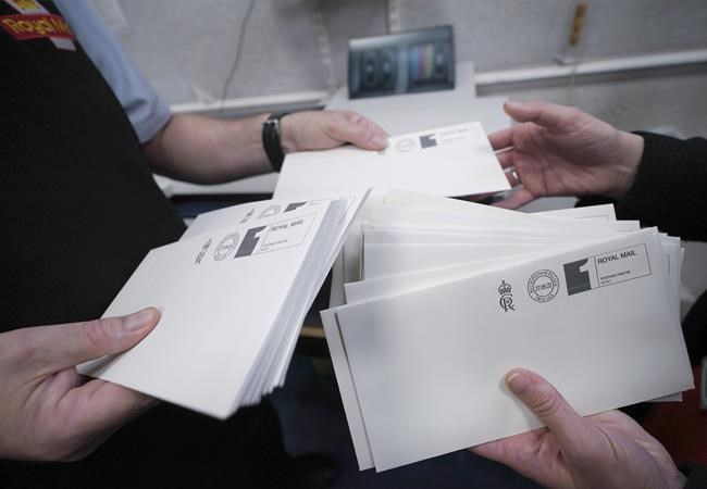 The first letters to be franked with the new cypher of Britain's King Charles III in the Court Post Office at Buckingham Palace, London, Tuesday Sept. 27, 2022. Along with the Royal Household mail the cypher will be used by government departments and appear on government buildings, state documents and on some post boxes in the coming months and years. (Yui Mok/Pool via AP)