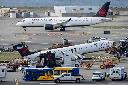 An Air Canada Express jet taxis past the wreckage of an Air Canada Express jet, Wednesday, March 25, 2026, as maintenance crews prepare to move the plane from the runway where it had collided with a Port Authority fire truck Sunday night at LaGuardia Airport, in New York. (AP Photo/Yuki Iwamura)