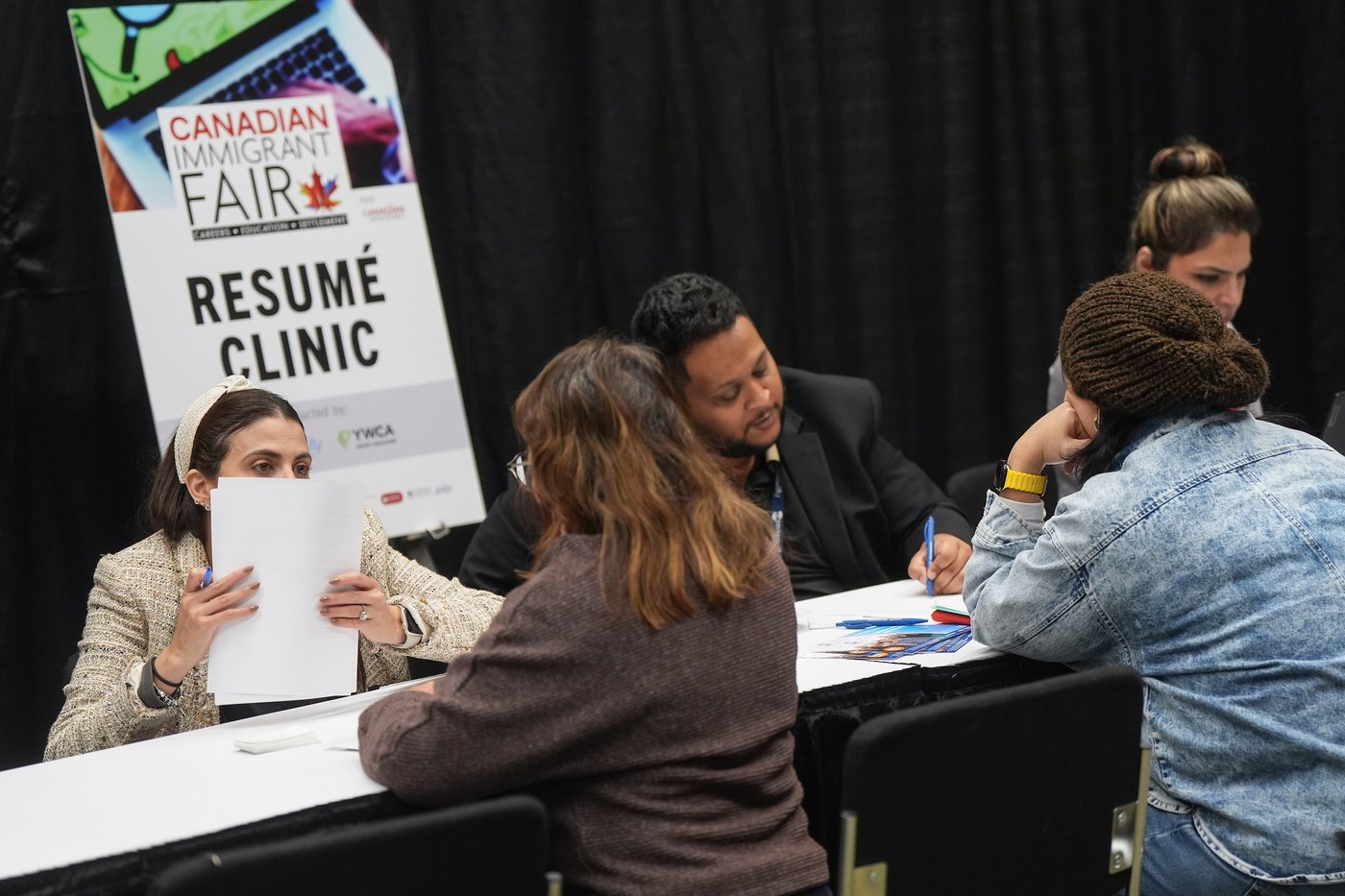 Job seekers get assistance with resumes at an immigrant job, career, education and settlement fair, in Vancouver, B.C., Wednesday, Oct. 29, 2025. THE CANADIAN PRESS/Darryl Dyck