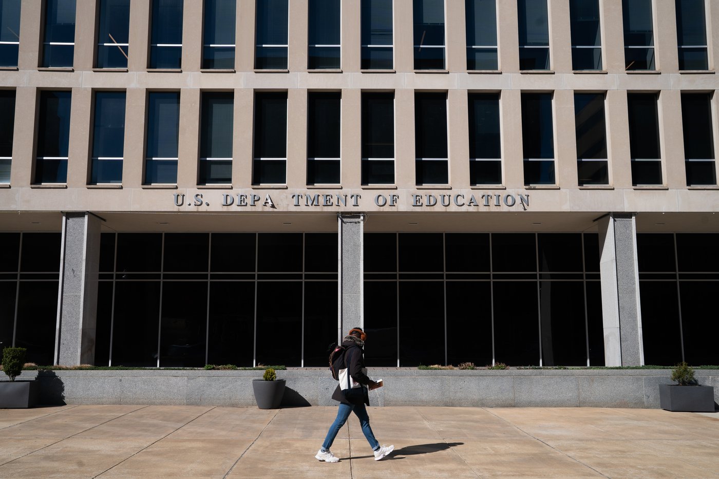 A person walks by the Department of Education building, seen with missing letters after removal of America 250 banners, Wednesday, March 18, 2026, in Washington. (AP Photo/Allison Robbert)
