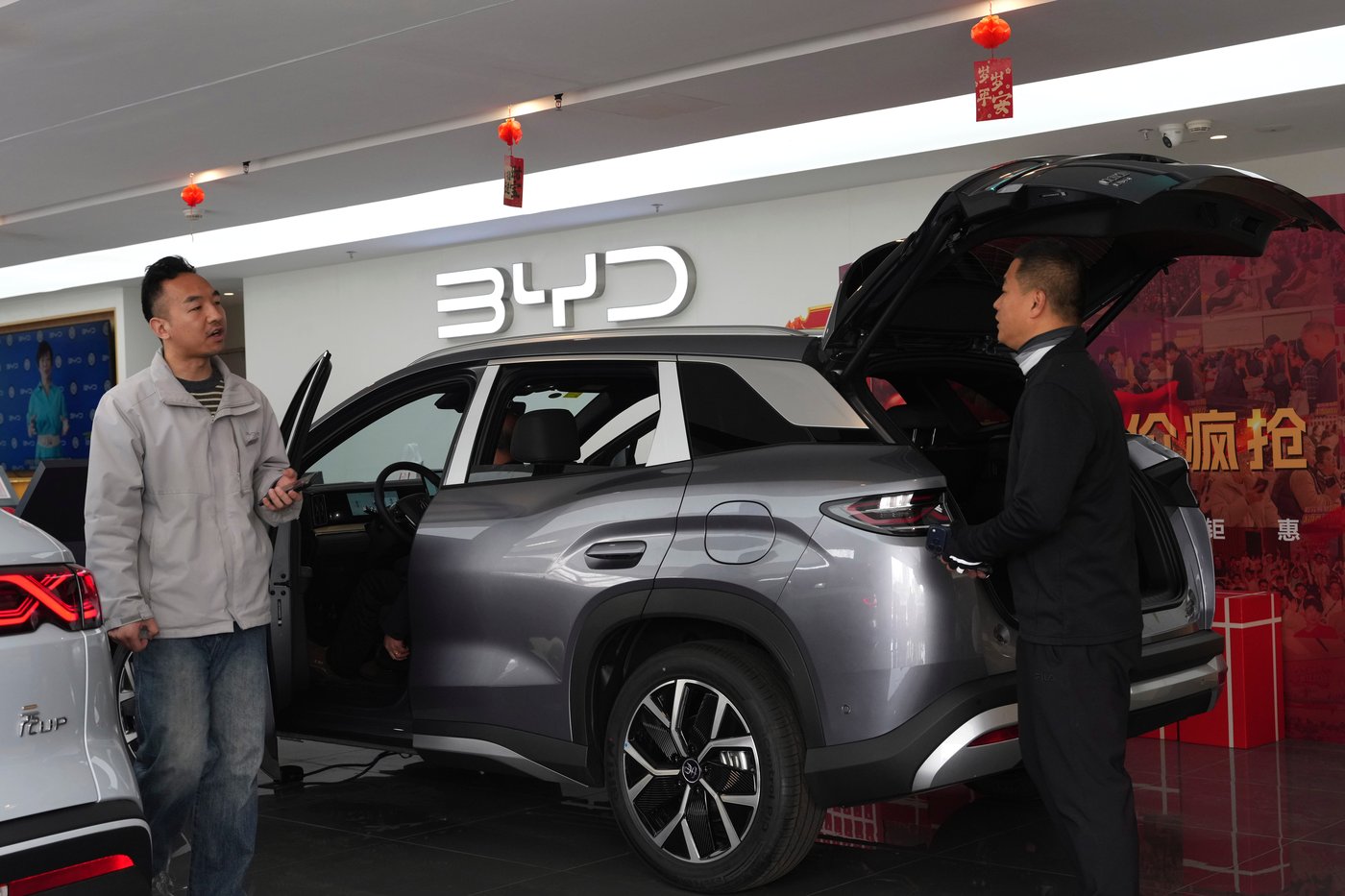 Visitors walk by a hybrid car at a BYD showroom in Beijing, China, Thursday, March 26, 2026. (AP Photo/Ng Han Guan)