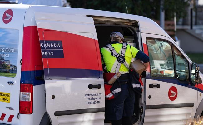 A Canada Post mail carrier delivers packages on their route in Montreal on Wednesday, Nov.13, 2024. Postal workers across the country could be off the job starting Friday if there's no breakthrough in contract negotiations with Canada Post - a disruption that would come just ahead of the busy Christmas holiday season. THE CANADIAN PRESS/Christinne Muschi