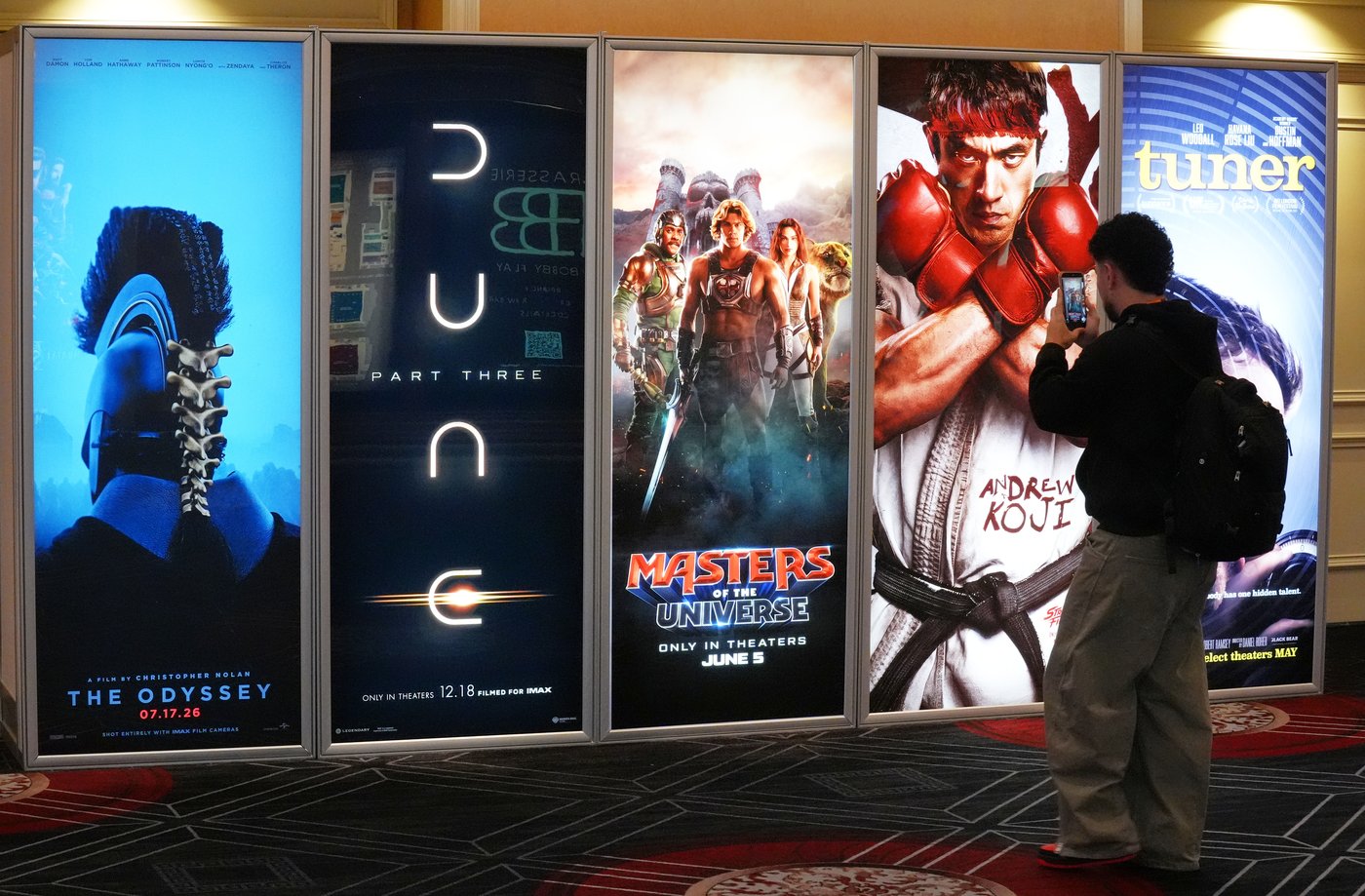 A CinemaCon attendee takes a picture of advertisements for upcoming films during the opening day of CinemaCon 2026, the official convention of Cinema United, on Monday, April 13, 2026, at Caesars Palace in Las Vegas. (AP Photo/Chris Pizzello)