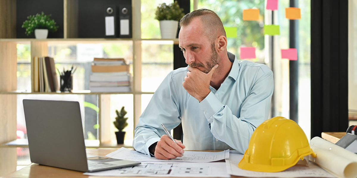 Man sits at a desk and looks at a laptop