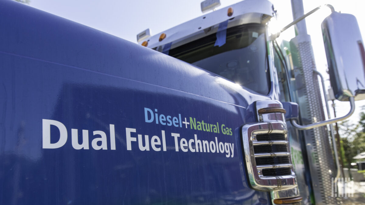 Blue Freightliner Coronado with graphic wrap detailing American Power Group's dual fuel technology.