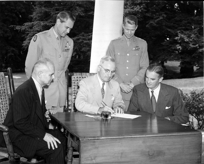 President Harry S. Truman signing a proclamation making August 1st Army Air Force Day. L-R: General James H. Doolittle (seated), President of the Air Force Association; Lieutenant General Hoyt S. Vandenberg (standing), Deputy Commander Army Air Force; President Truman (seated); Major General Lauris Norstad (standing), Director of Plans and Operations, War Department, General Staff; W. Stuart Symington (seated), Assistant Secretary of War for Air. (Photo: trumanlibrary.gov)